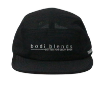 Front panel of a black hat with a white Bodi Blends logo stitched into the front. The cap is made of 100% recycled polyester.